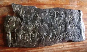 Plaque de métal gravée de lettres latines, possiblement une inscription trouvée près de la tour de Saint-Lupicin.