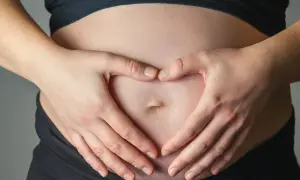 Dłonie tworzą serce na brzuchu, symbolizując miłość i troskę o to, jak dziecko oddycha w brzuchu.