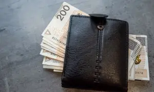 Czarny portfel z polskimi banknotami. Zastanawiasz się, jak obliczyć chorobowe w ciąży? Finanse przyszłej mamy.