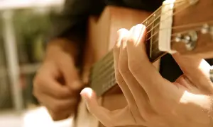 Dłonie grające na gitarze, tworząc dźwięki, które mogą wywołać uczucie lacrimosa.