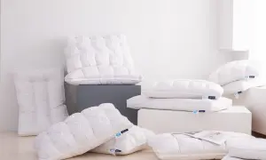 A pile of fluffy white down pillows, some with tufted patterns. One new down pillow smells bad, but the others look inviting.