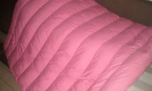 Miękka, różowa pierzyna z wyraźnymi przeszyciami, która zaprasza do przytulnego odpoczynku.