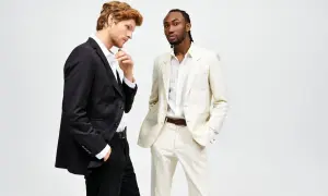 Due uomini in abiti eleganti. Uno con giacca nera e pantaloni neri, l'altro con giacca e pantaloni color crema. Il **slim fit significato** è evidente nella vestibilità moderna.