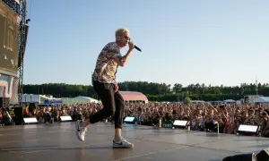 Wokalista One Republic na koncercie, śpiewa do mikrofonu na scenie przed rozentuzjazmowanym tłumem fanów.