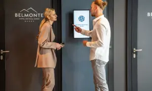 Elegancko ubrana para dyskutuje przy ekranie informacyjnym w hotelu Belmonte.
