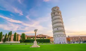 La Torre di Pisa, con il suo fascino inclinato, è al centro di una ricerca visiva, circondata da un prato verde e un cielo al tramonto.