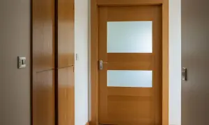 Jak przerobić stare drzwi z szybą na nowoczesne? Drewniane drzwi z dwoma matowymi przeszkleniami i metalową klamką.