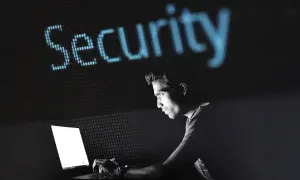 Mężczyzna pracuje przy laptopie, nad nim świeci się napis "Security". Dowiedz się, jak zahasłować plik Excel, aby chronić swoje dane.