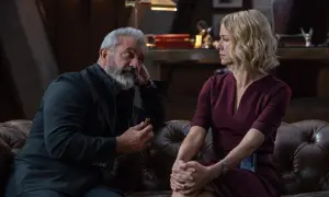 Mel Gibson w filmie, z cygarem w dłoni, rozmawia z kobietą w bordowej sukience.