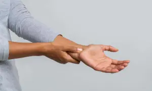 Eine Person hält sich das Handgelenk, als ob sie ein Ziehen im Handgelenk spürt.