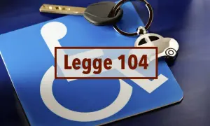Chiave e portachiavi a forma di auto su un cartello blu con simbolo disabili e testo "Legge 104".