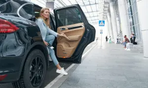 Kobieta wysiada z luksusowego SUV-a, trzymając dokumenty, które mogą być związane z umową użyczenia samochodu.