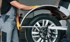 Mechanik w żółtych rękawiczkach dokonuje doważania kół na samochodzie, dbając o płynną jazdę.