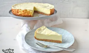 Ein cremiger american cheesecake mit Keksboden, ein Stück auf einem Teller mit Gabel.