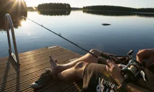 Spokojne popołudnie nad jeziorem wyrówno. Wędkarz czeka na branie, słońce odbija się w wodzie.