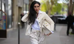 Eleganckie białe spodnie w stylizacji z kremową marynarką i torebką. Stylowy pasek z kluczykami dodaje uroku.