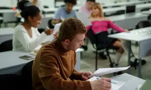Studenci w sali wykładowej, zastanawiający się, czy można iść na studia bez matury.