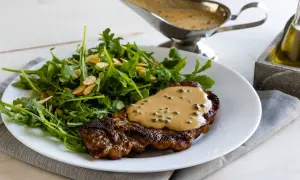 Un succulento filetto al pepe verde, nappato con salsa cremosa, servito con un'insalata fresca di rucola e mandorle.
