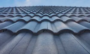 Szara, falista angoba dachówka tworzy gładką, jednolitą powierzchnię pod błękitnym niebem.