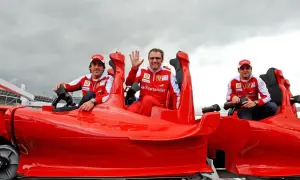 Trzech mężczyzn w strojach Ferrari siedzi w czerwonym wagoniku, który wygląda jak najszybszy rollercoaster na świecie.