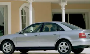 Srebrne Audi A4 B5 stoi przed eleganckim budynkiem z kolumnami.