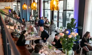W restauracji "Polskie Smaki" goście delektują się posiłkami przy elegancko nakrytych stołach, w otoczeniu nowoczesnego wystroju i ciepłego światła.