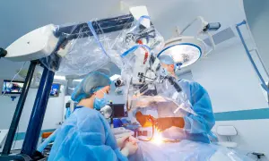 Chirurdzy w sterylnych strojach prowadzą skomplikowaną operację neurochirurgiczną pod mikroskopem.