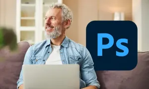 Uśmiechnięty mężczyzna z laptopem i logo Photoshopa.