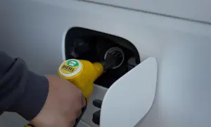 Ręka trzymająca żółtą dyszę dystrybutora z napisem DIESEL B10, tankująca samochód.