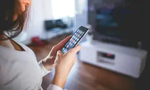 Kobieta przegląda aplikacje na telefonie, szukając sposobu, jak wyczyścić pamięć w telefonie, by zwolnić miejsce.
