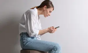 Frau mit schlechter Haltung, die auf ihr Handy schaut. Ihr Rücken ist gekrümmt, was zu einem Buckel am Nacken führt.