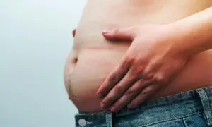 Une main touche un ventre proéminent, soulevant la question : le pain complet fait-il grossir le ventre ?