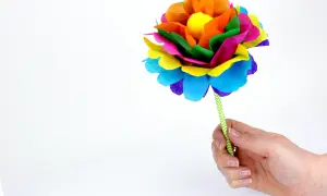 Une fleur en papier Canson facile, aux couleurs vives, tenue par une main.