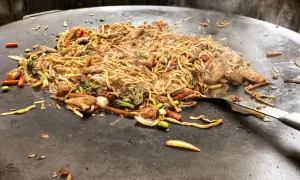 En wok med nudlar, kyckling och grönsaker tillagas på en muurikka. Ett perfekt recept för en muurikka wok!