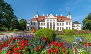 Pałac Zamoyskich w Kozłówce otoczony kwitnącym ogrodem z fontanną i rzeźbą.