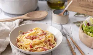 Un plat de spaghetti crémeux, garni de lardons croustillants, évoque la vraie recette carbonara italienne. Une salade fraîche accompagne ce délice.