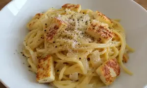 En krämig vegetarisk carbonara med spaghetti, stekt halloumi och rikligt med parmesanost och svartpeppar.