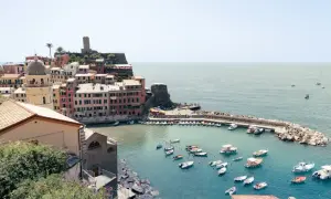 Bunte Häuser am Hafen von Cinque Terre, Italien, mit vielen Booten im türkisfarbenen Wasser.