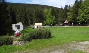 Przełęcz Krowiarki, z pomnikiem i chatkami, otoczona lasem.