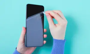 Ręce nakładają folię ochronną na ekran telefonu. Czy folia ochronna na telefon to dobry pomysł? Warto zabezpieczyć ekran.
