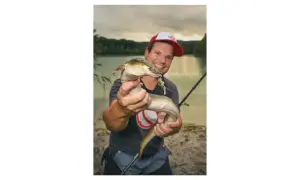 Glücklicher Angler hält einen Aal, der an einer Fischfetzen-Montage hängt.