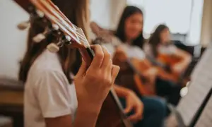 Dziewczyny ćwiczą grę na gitarach w szkole muzycznej.