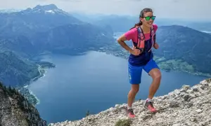 Läuferin im Gebirge, die zeigt, wie verbessere ich meine ausdauer durch anspruchsvolles Gelände. Bergsee und Gipfel im Hintergrund.