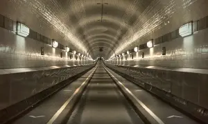 Der lange, beleuchtete Gang des alten Elbtunnels mit seinen gekachelten Wänden und Lichtern, die eine Perspektive erzeugen.
