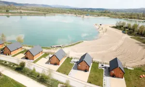 Drewniane domki nad turkusową wodą, idealne na wypoczynek w stylu kąpielisko Mała Chorwacja. Piękny piasek i zieleń wokół.