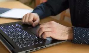 Dłonie pracują na laptopie z podświetlaną klawiaturą. Procesor AMD Ryzen 5 5600H zapewnia płynność pracy.