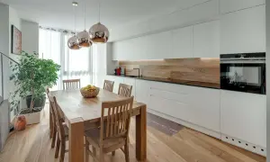 Tavolo in legno con sedie, ideale per chi vuole ristrutturare cucina. Illuminazione moderna e mobili bianchi.