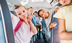 Dzieci w autobusie szkolnym robią sobie zdjęcie. Dziewczynka z przodu robi dziubek i znak pokoju. Wszyscy wyglądają na szczęśliwych, co świadczy o ich niekaralności na tle seksualnym.