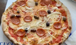 Eine köstliche Pizza mit Salami, Zwiebeln und Oliven, frisch aus i due forni.