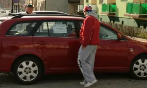 Czerwony samochód na sprzedaż z ogłoszeniem na szybie. Cena 26000. Zastanawiasz się, ile kosztuje wystawienie samochodu na OLX?